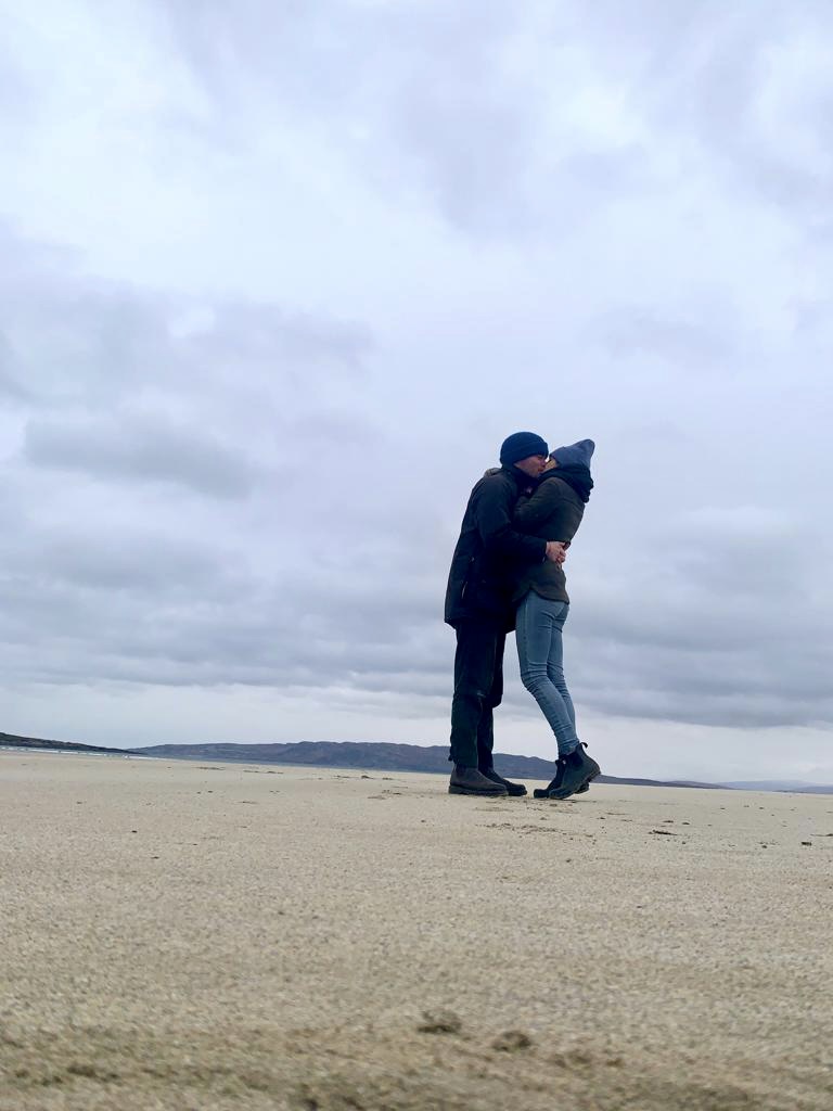 Valentine and Vincent kissing on a windy beach